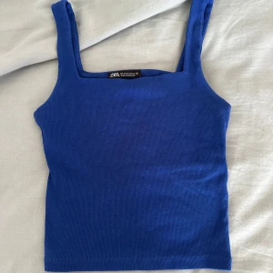 Blå ribbad linnetopp från Zara - Det Snygg blå linnetopp från Zara i storlek S. Toppen har breda axelband och är ribbad för en cool och enkel look. Perfekt att matcha med jeans eller kjol. Materialet är mjukt och stretchigt, vilket gör den superbekväm att bära.