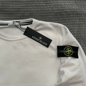 Vit tröja från Stone Island - Vit långärmad tröja från stone island som är i nytt skick. Vid snabb affär kan jag gå ner lite i pris men eftersom den är ny så kan jag inte ge bort den ”gratis”. Skriv vid funderingar!