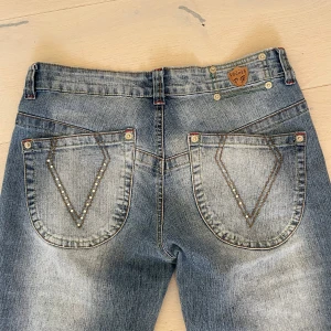Lågmidjade bootcut jeans - Snygga blå jeans från vintage i Köpenhamn. Både fram- och bakfickorna är dekorerade. Jeansen är bootcut och helt nya.