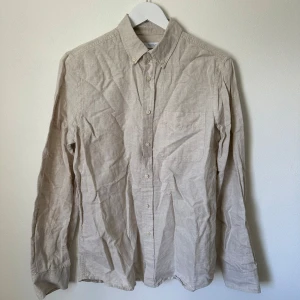 Beige linneskjorta från Zara, S - Snygg beige skjorta från Zara i storlek S, tillverkad i en skön mix av linne och bomull. Klassisk modell med knappar framtill, bröstficka och lång ärm. Perfekt för en clean och avslappnad look. B358