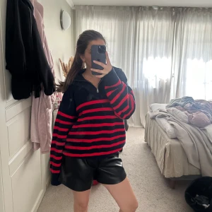Randig stickad tröja med half zip - Mysig stickad tröja med mörkblå och röda ränder, half zip framtill och långa ärmar. Oversized passform som ger en chill vibe. Perfekt att dra på sig när det är lite kallare ute. Tröjan har ribbade muddar och är riktigt mjuk.