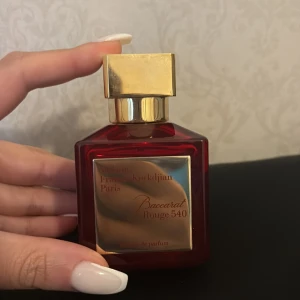 Baccarat Rouge 540 Extrait 70ml - Lyxig parfymflaska i rött glas med guldiga detaljer och fyrkantig form. Maison Francis Kurkdjian Baccarat Rouge 540 Extrait de Parfum, 70 ml. Flaskan har en elegant guldig etikett och matchande guldlock. Perfekt för dig som gillar exklusiva dofter. Parfymen är använd!! Försökte visa tydligt hur mycket som är kvar! Köpt på nk för 4100 kr, seriösa köpare kan få se orderbekräftelse kvitto etc