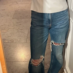 Blå ripped jeans från Zara, strl 36 - Säljer ett par blå jeans från Zara i storlek 36. Jeansen har raka ben och snygga slitningar. Perfect för hösten med en stivkad tröja och skor.