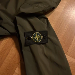 Stone Island grön vindjacka  - Riktigt skön Stone Island windbreaker till hösten! Jackan har inga riktiga defekter, en av knapparna har ramlat av och sytts på men det märker man inte av. Jackan är i en äldre modell och har därför inte certilogo qr-koden. Den är med hög sannolikhet äkta men jag har inget exakt bevis då jag köpte den begagnad på vinted👍 Hojta till  om ni har frågor eller funderingar! Priset är absolut inte hugget i sten!