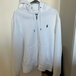 Vit hoodie från Polo Ralph Lauren - Säljer denna vita ralph lauren zip hoodien som är perfekt nu för hösten. Den är inprincip i ny skicka då den inte kommit till användning, skriv för fler bilder med mera😁