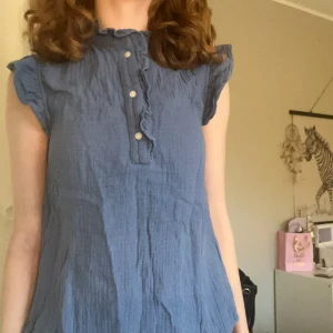 Blå blus med volang och knappar - Supersöt blå blus som jag inte använder längre🦋💙Har knappt använt den och det finns inga täcken på hål eller skador, det är storlek XS men skulle säga att den passar storlek S oxå❤️
