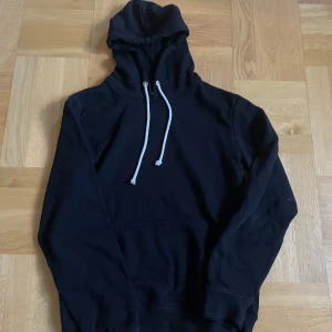 Pier one  - Svart hoodie med vit snörning i huvan och klassisk magficka. Tröjan har lång ärm och en skön, loose passform som passar perfekt för chill dagar. Materialet känns mjukt och bekvämt mot huden. Enkel och stilren design som funkar till det mesta.