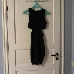 Svart tight klänning med cut-out  - Svart tight klänning från NA-KD i storlek XS. Klänningen är kort med cut-out-detaljer i midjan som ger en snygg siluett. I fint skick. Använd fåtalgånger. KAN ABSOLUT GÅ NER I PRIS VID SNABB AFFÄR ELLER BUNDLE!