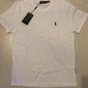 Vit t-shirt från Polo Ralph Lauren - Klassisk vit t-shirt från Polo Ralph Lauren med liten broderad logga på bröstet. T-shirten har rund halsringning och korta ärmar. Perfekt basplagg med stilren design.