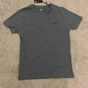 Blå t-shirt från 157 med tryck - Säljer en stilren blå t-shirt från 157 med diskret tryck 'Rain Days' på bröstet. T-shirten har rund hals och korta ärmar, perfekt för en avslappnad look. Gjord i mjukt bomullsmaterial. Köpte den för mig själv och deb var för liten och jag tapade bort kvittot.Jag köpte den för 60kr 