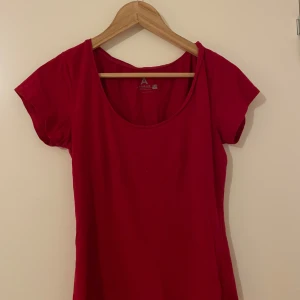Röd t-shirt från Åhléns - En enkel och klassisk röd t-shirt från Åhléns i mjuk bomull. T-shirten har rund halsringning och korta ärmar. Perfekt att matcha med jeans eller kjol för en färgstark look.