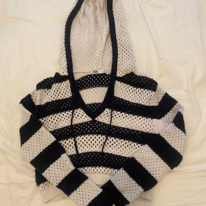 Randig stickad hoodie från ZARA - Säljer en stickad hoodie från ZARA med breda svarta och vita ränder. Tröjan har luva med v-ringning. Perfekt för en avslappnad och trendig look.