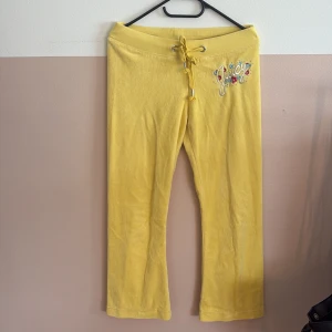 Gula mjukisbyxor från Juicy Couture - Snygga gula mjukisbyxor från Juicy Couture med broderad logga och blommor framtill. Perfekta för en avslappnad och trendig look. Storleken är m men de är ganska korta! Skriv till mig innan ni trycker på köp nu!✨