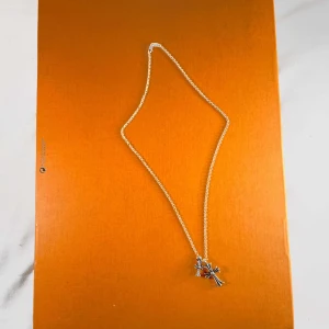 Silverhalsband med korshängen från Chrome Hearts - Säljer ett snyggt silverhalsband från Chrome Hearts med två korshängen i olika storlekar. Kedjan är tunn och detaljerad, och båda korsen har en klassisk design med fina detaljer. Perfekt för dig som gillar statement-smycken. Priset är inte skrivet i sten men kom privat om du har några funderingar