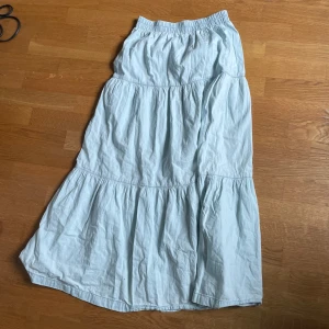 Ljusblå långkjol från Stradivarius - Säljer en ljusblå långkjol från Stradivarius i storlek XS. Kjolen har resår i midjan och flera volanger som ger en luftig och avslappnad känsla. Perfekt för varma dagar och enkel att matcha med olika toppar.