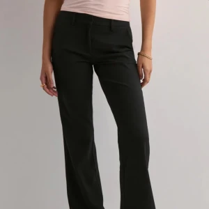 Svarta kostymbyxor med bootcut - Snygga svarta kostymbyxor med klassisk bootcut-passform och normal midja. Byxorna har hällor för bälte och stängs med dragkedja och knapp framtill. Perfekta för en stilren look.