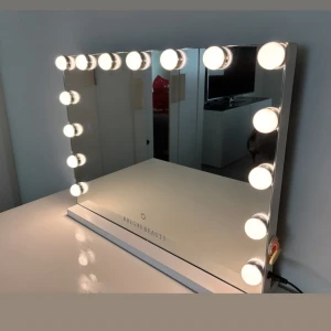 Sminkspegel med LED-lampor från Bright Beauty - Stor sminkspegel med ram av vita LED-lampor som ger perfekt belysning för sminkning. Spegeln har en modern design med vit bas och tydlig spegelyta. Perfekt för att få till detaljerna i din makeup.