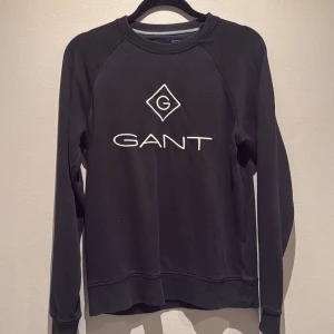 Svart sweatshirt från Gant - Svart sweatshirt från Gant med vit broderad logga på bröstet. Tröjan har rund halsringning och långa ärmar. Perfekt för en avslappnad och stilren look. Storlek S men passar även M. Priset gör att diskutera.