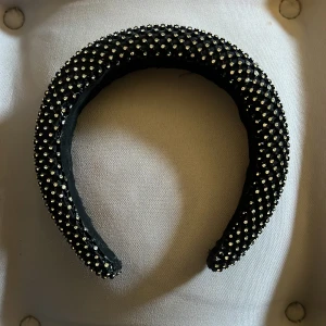 Svart diadem med pärlor - Snyggt svart diadem med tätt placerade små pärlor över hela ytan. Diademet är brett och ger en trendig look, perfekt för att lyfta vilken outfit som helst.