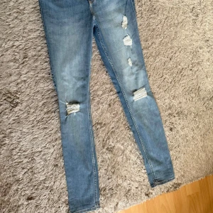 Jeans - Höga jeans från Hollister med slitningar framtill. Storlek W27 L28, 5R. Passar mig som är 170cm.