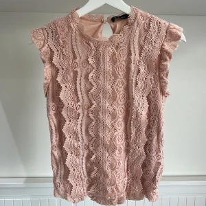 Rosa spetstopp med volangkant - Säljer en ljusrosa ärmlös topp i spets med fina vågiga detaljer och volangkant. Toppen har hög halsringning och är helfodrad. Perfekt för dig som gillar romantisk stil. 4st rosa toppar, varje säljs för 30kr.