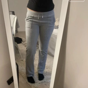 Grå mjukisbyxor från Juicy Couture - Säljer ett par grå mjukisbyxor från Juicy Couture i storlek S. Byxorna har normal passform, dragsko i midjan och fickor både fram och bak. Perfekta för en avslappnad stil och riktigt sköna att ha på sig.