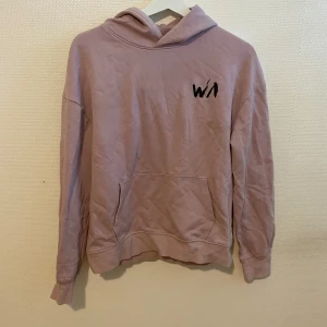 Rosa hoodie - Säljer en rosa hoodie från Stadium med tryck framtill och en cool illustration av en tjej med skateboard och blomma på ryggen. Hoodien har magficka och långa ärmar. Perfekt för dig som gillar streetstyle!