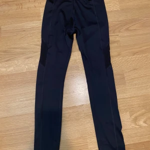 Svarta träningstights - Svarta träningstights från SOC med smal passform. Tillverkade i syntetmaterial som andas och håller dig torr och bekväm under träning. Perfekta för sportaktiviteter och har diskreta sömmar längs benen.