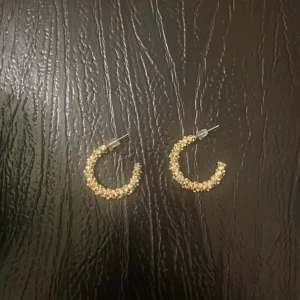 Guldiga creolörhängen med pärldetaljer - Säljer ett par snygga creolörhängen i guld med små pärldetaljer runt hela ringen. Perfekta för att ge din outfit lite extra glans och stil.