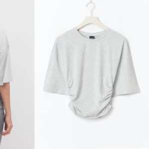 Ljusgrå topp från lager 157 - Ljusgrå topp med korta ärmar och från lager 157z T-shirten har en lös passform upptill och rynkade detaljer i sidorna framtill som ger en snygg midja. Tillverkad i mjuk bomullsmix, perfekt för en avslappnad stil. Aldrig använd.