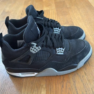 Svarta Nike Air Jordans sneakers - Säljer ett par svarta Nike Air Jordans med grå och silvriga detaljer. Skorna har snörning, meshpaneler på sidorna och en platt sula med röd logga undertill. Perfekta för dig som gillar klassiska och sportiga sneakers. Köpta i USA på lyx sneaker shop, lite färg defekter men annars typ helt nya. Nytt pris 5000