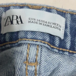Blå högmidjade jeans från Zara - Klassiska blå jeans från Zara med hög midja och raka ben. Jeansen har fem fickor och stängs med dragkedja och knapp. Perfekta till vardags för en avslappnad men snygg look.