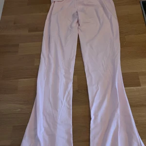 Ljusrosa yogapants från Gina Tricot - Säljer ett par ljusrosa bootcut byxor från Gina Tricot. Byxorna har en utsvängd passform och är tillverkade i ett mjukt material som känns bekvämt mot huden. Perfekta för dig som gillar en trendig och avslappnad stil.