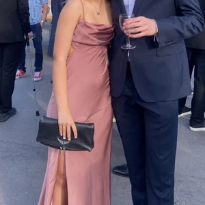 Rosa balklänning - Säljer min eleganta balklänning i skimrande rosa med smala axelband och draperad urringning. Klänningen har en hög slits framtill och öppen rygg med knäppning. Perfekt för bal eller fest! Materialet har en satinliknande finish. Materialet är tjockt vid bysten så bh behövs ej! Passar både mindre och större bröst (testat), använd en gång💗😍💞 Storlek 34 men passar mig frf som nu har 38💞