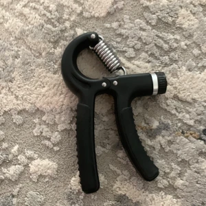 Handtränare med justerbart motstånd - Ett svart handträningsredskap med justerbart motstånd, perfekt för att stärka greppstyrka och underarmar. Passar både nybörjare och träningsentusiaster som vill förbättra sin handstyrka hemma eller på gymmet.