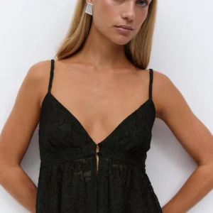 Svart spetslinne med smala axelband - Säljer ett svart linne från Gina Tricot med smala axelband och v-ringning. Toppen är dekorerad med spets och har en liten knappdetalj framtill. Perfekt för sommaren och enkel att styla till olika outfits.❤️