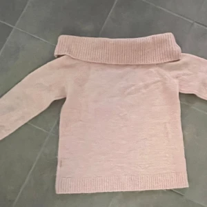 Ljusrosa offshoulder stickad tröja - Superfin ljusrosa stickad tröja med bred offshoulder-krage. Tröjan har långa ärmar och ribbade muddar vid ärmslut och nederkant. Perfekt för dig som gillar en mysig och trendig stil. Säljer pga att den inte kommer till andvänding. Perfect att ha till en mysig sommar kväll 