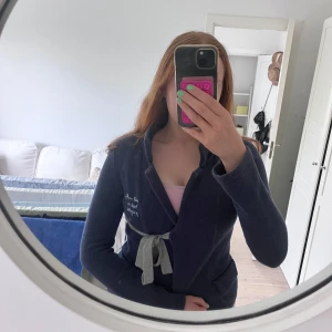 Mörkblå fleecejacka med bälte från Odd Molly - Mysig mörkblå kofta från Odd Molly med krage och ljusgrått knytbälte i midjan. Jackan har broderad text på bröstet och två fickor framtill. Perfekt finare kofta för middagar eller mys!💗💗