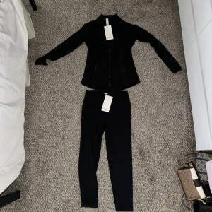 Svart träningsset från Lululemon - Hej!  Säljer flickvännens lululemon set som hon köpte för några månader sedan och aldrig kommit till användning,  Dom är endast testade 1 gång så aldrig riktigt använda med taggarna kvar,  Storlek 8 vilket ska motsvara storlek M/ storlek 40 Först till kvarn gäller! 