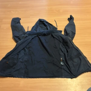 Blå parkajacka från Polo Ralph Lauren - Säljer en blå parkajacka från Polo Ralph Lauren med huva och flera fickor framtill. Jackan har dragsko i midjan och knäppning med både dragkedja och knappar. Perfekt för kyligare dagar.