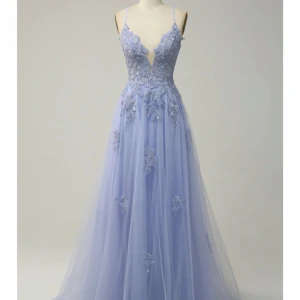 Ljusblå långklänning med spets och blommiga detaljer - Säljer en drömmig ljublålångklänning med tunna axelband och djup v-ringning. Klänningen har vackra spets- och blommiga applikationer på livet och tyllkjol som ger en romantisk känsla. Perfekt för bal eller fest!