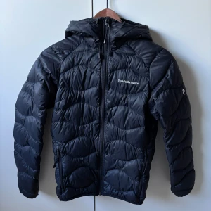 Svart dunjacka från Peak Performance - Säljer min Peak Performance Helium-jacka! Ord pris: ca 3000kr. Mitt pris: 500kr. Modellen är lätt, vindtät och perfekt både som ytterjacka och under skaljacka. Det finns ett litet hål i vänster arm men som lätt går att laga (kolla sista bilden). Skriv vid frågor eller om du vill ha fler bilder!