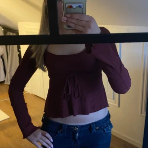 Vinröd topp med knyt - Säljer en vinröd långärmad topp från nelly. Toppen har en rundad urringning och lätt utsvängd nederkant. Perfekt för dig som gillar en feminin och trendig stil. Har används fåtal gånger och är i mycket bra skick. Hör av dig vid frågor eller interesse💞
