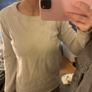 Beige stickad tröja - Säljer en stilren beige stickad tröja med rund halsringning. Tröjan har långa ärmar och ribbade kanter vid ärmslut och nederkant. Perfekt för en avslappnad look.