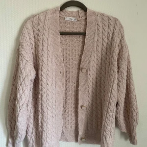 Ljusrosa  stickad kofta från MNG - Säljer en ljusrosa stickad kofta från MNG med ett snyggt flätmönster. Koftan har långa ärmar och knappar framtill. 
