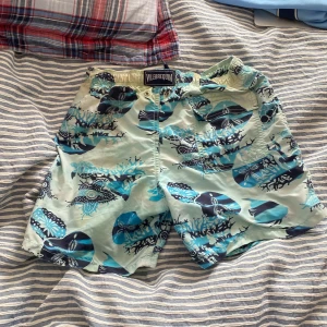 Två par badshorts från Vilebrequin - Säljer två par snygga badshorts från Vilebrequin. Ena paret är ljusblå med havsinspirerat mönster i blått och svart, det andra är marinblå med gröna sköldpaddor.                                                               Size S 