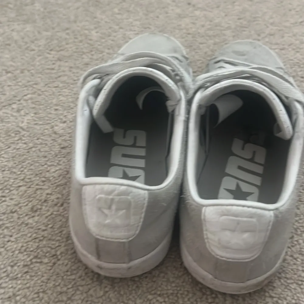 Säljer ett par grå sneakers från Converse med den klassiska stjärnloggan på sidan. Skorna har snörning och en vit sula. Perfekta för en avslappnad stil.. Kengät.