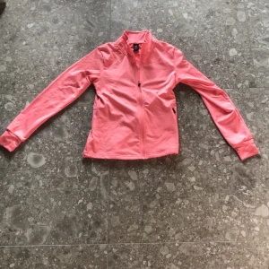 Rosa träningsjacka från SOC - Säljer en rosa träningsjacka från SOC i storlek 146-152. Jackan har dragkedja framtill, hög krage och långa ärmar. Perfekt för träning eller som ett extra lager under kyliga dagar.