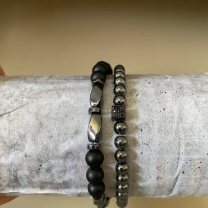 Två st pärl armband i svart och silver - Säljer två snygga armband med pärlor i svart och silver. Det ena har mattsvarta och blanka silverfärgade pärlor, det andra har små silverpärlor och en dekorativ kubdetalj. Perfekta för att lyfta din outfit. Perfekt att matcha med vänner eller bara vill fixa din outfit!