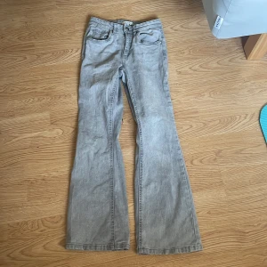 Grå bootcut jeans från Denim Day - Säljer ett par gråa jeans från Denim Day i storlek 152. Byxorna har klassisk femficksdesign, knapp och dragkedja framtill samt bootcut-ben. Perfekta för dig som gillar en lite vidare passform nertill.